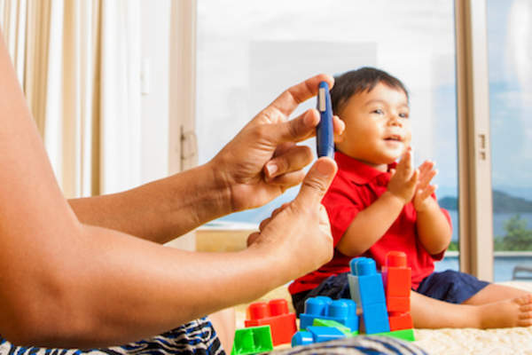 妈妈在宝宝玩耍时测血糖。