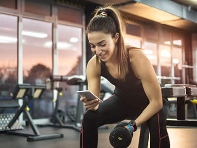 在健身房女子用她的手机来追踪运动的进步。