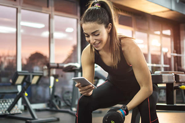 在健身房女子用她的手机来追踪运动的进步。