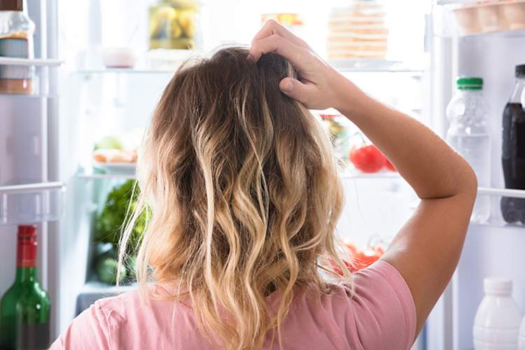 女人无法决定她想要从冰箱里吃什么。