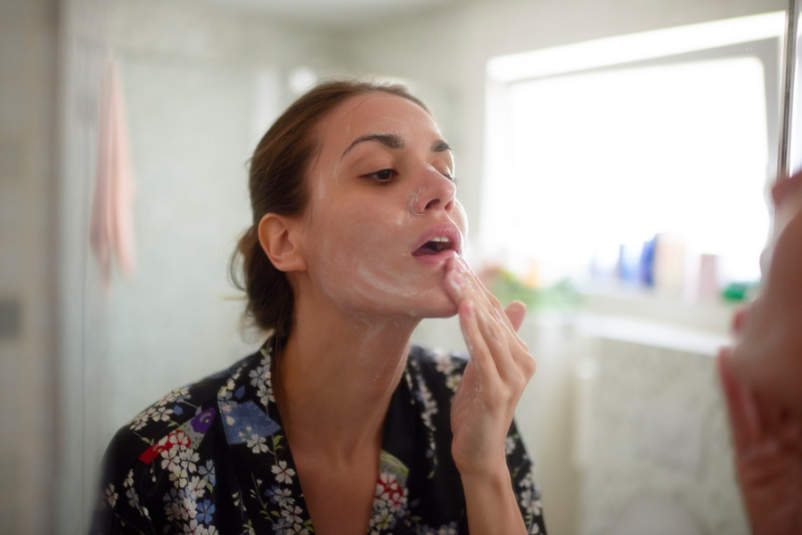 女人在浴室里检查脸和护理皮肤