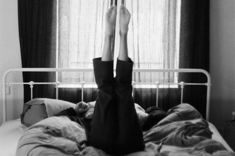 black and white photo of person in bed with legs sticking straight up