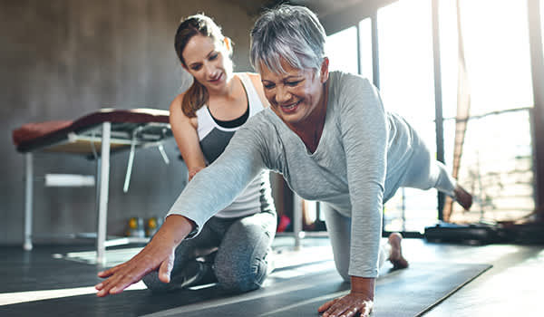 老年妇女锻炼与教练的形象。