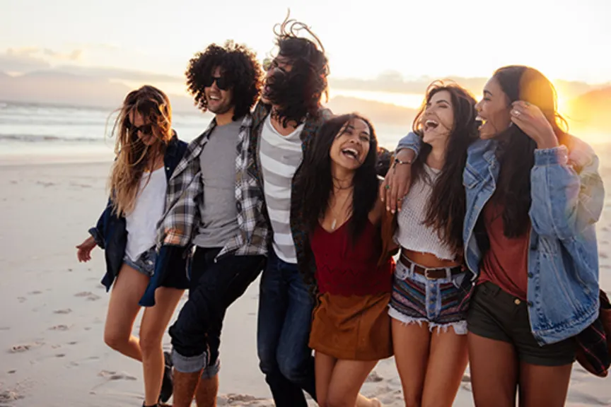 Hipster friends embracing joyfully at sunset on seaside