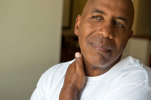 男人在抚摸在他的脖子上的肿块。