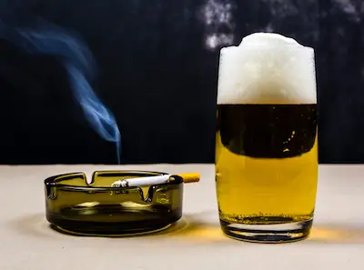 香烟放在烟灰缸里，旁边是啤酒。