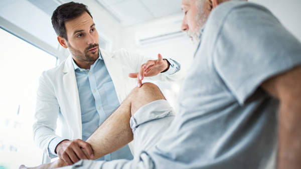 疼痛专家检查关节炎疼痛患者的膝盖。