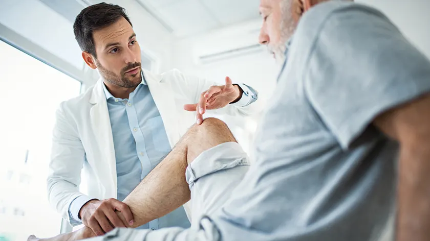 疼痛专家正在检查患有关节炎的病人的膝盖。