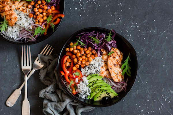 烤鸡,米饭,辣鹰嘴豆,鳄梨,卷心菜,在黑暗的背景辣椒佛碗。