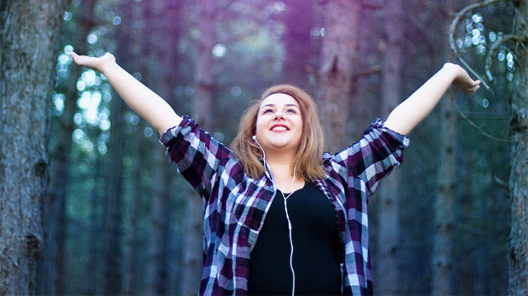 幸福的女人走在树林里听音乐。