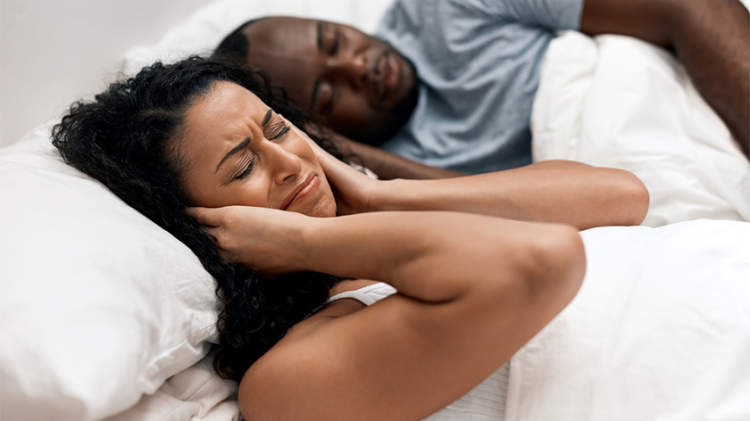女人在床上捂着耳朵，男人在打呼噜。