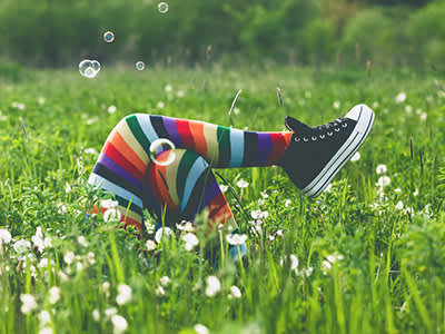 独特的人躺在高高的绿草地上，穿着五颜六色的袜子吹泡泡。