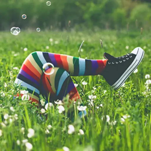 独特的人躺在高高的绿色草地上，穿着五颜六色的袜子，吹着泡泡。