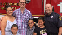 消防员史蒂夫·德卢卡和家人在消防站的一辆卡车前摆姿势。