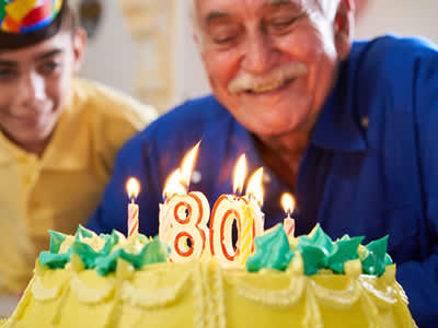老人在吹灭生日蛋糕蜡烛。