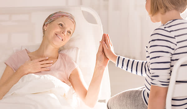 母亲患有乳腺癌微笑着抚摸她女儿的手。