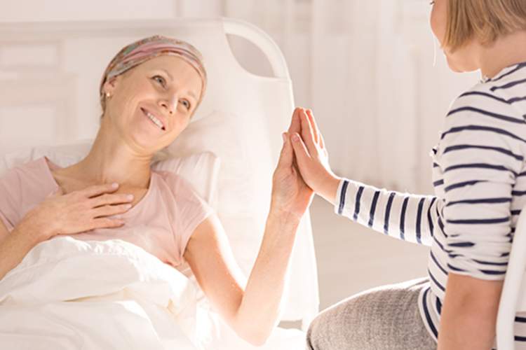 患乳腺癌的母亲微笑着抚摸女儿的手。