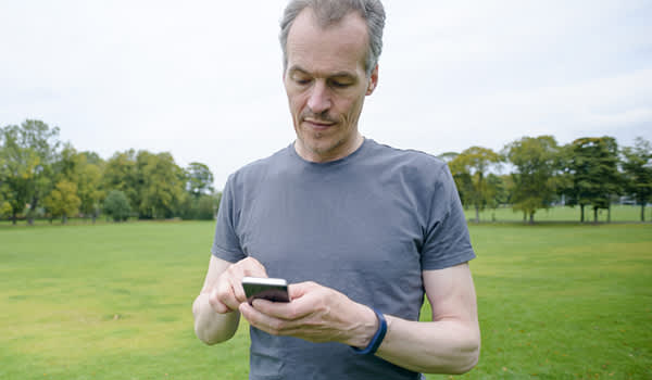 中年男性跑步者与智能手机应用程序。