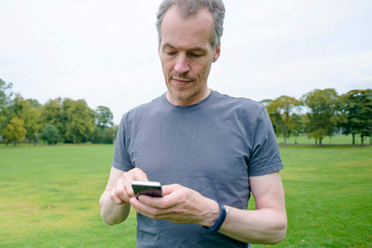 中年男性跑步者与智能手机应用程序。