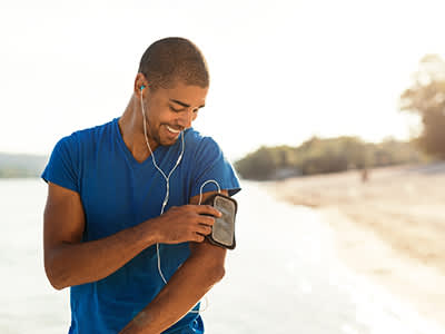 健康，微笑的男人听着音乐出去跑步。