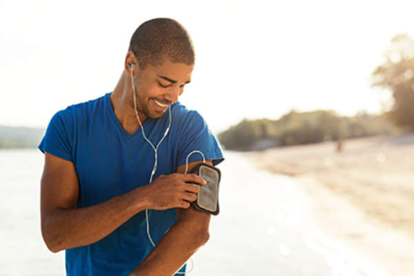 健康,微笑的男人听着音乐出去跑步。