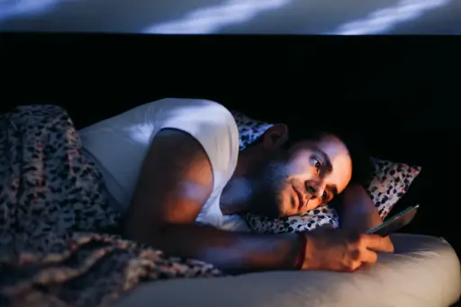 年轻人使用智能手机晚上躺在床上