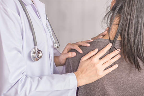 医生检查女性的颈部和肩部。