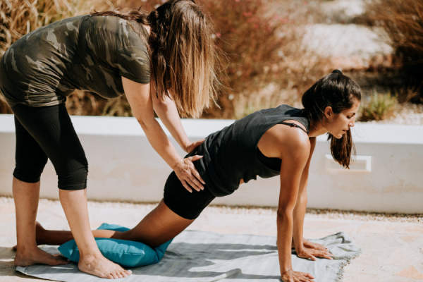 女人与教练的帮助瑜伽伸展时