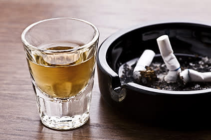 酒精旁边的香烟在烟灰缸。