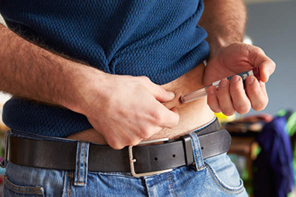 Diabetic man injecting insulin into his stomach.