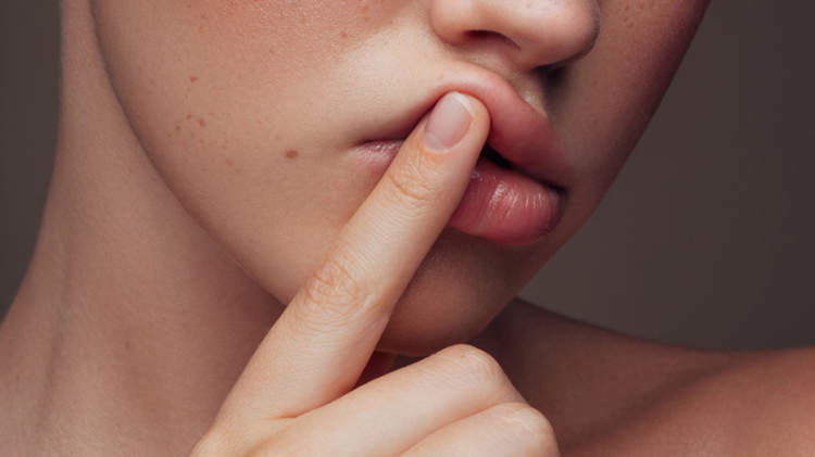 一个年轻的女人把手指放在嘴唇上。