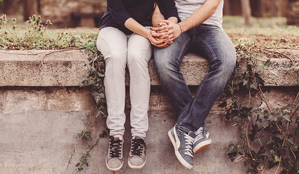 情侣手牵着手,而坐在墙上。