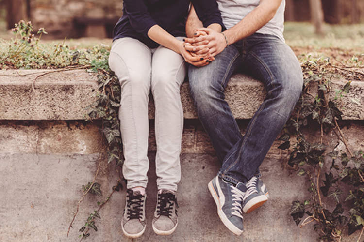 情侣手牵着手,而坐在墙上。
