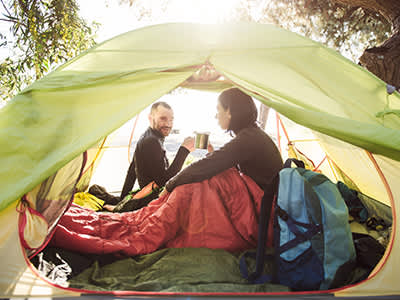 坐在帐篷里喝咖啡的夫妇。