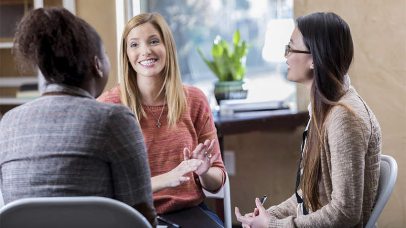 快乐的年轻女性在小组治疗中交谈。