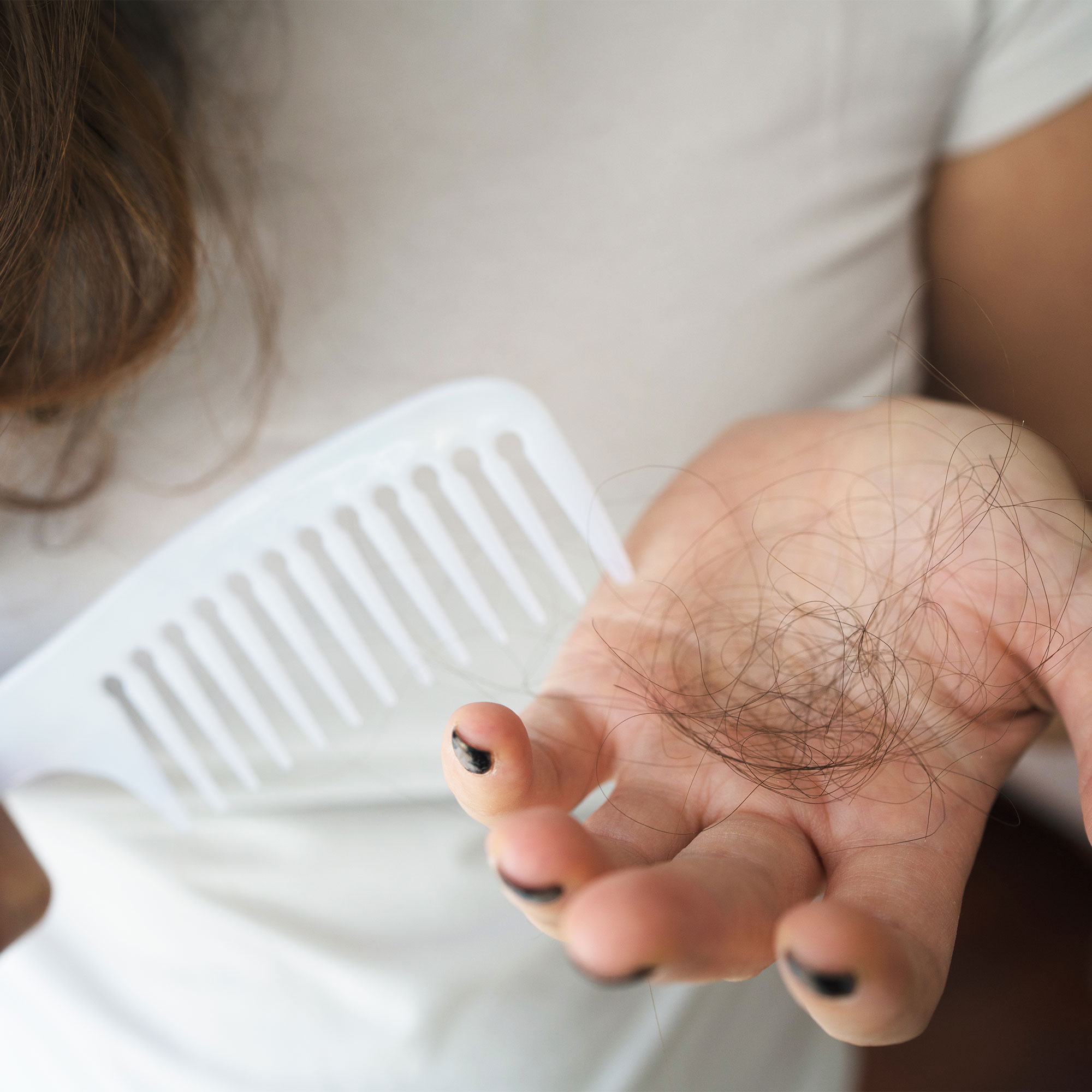 的特写镜头,一个女人拿着一撮头发和一把梳子