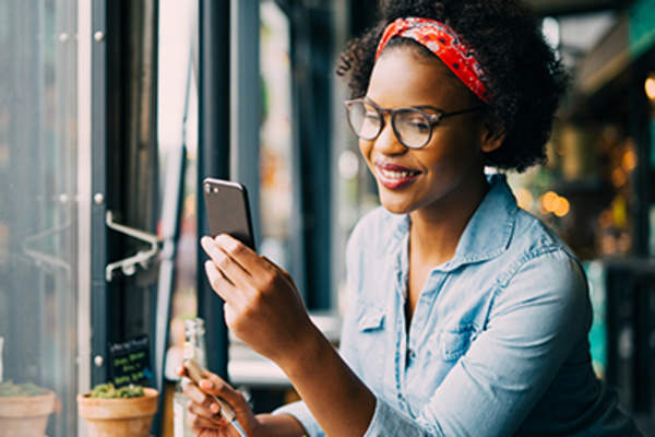 一位女士在一家小酒馆里看着自己的智能手机,面带微笑。