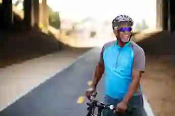 一个快乐的男人拿着自行车站在一条小路上