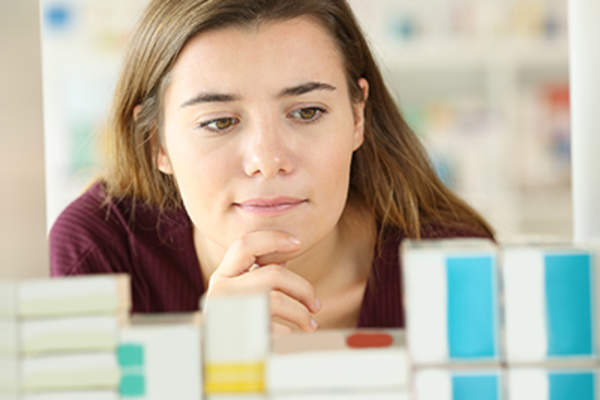 Woman reading labels on boxes at a pharmacy.
