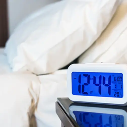 Digital alarm clock on a nightstand.