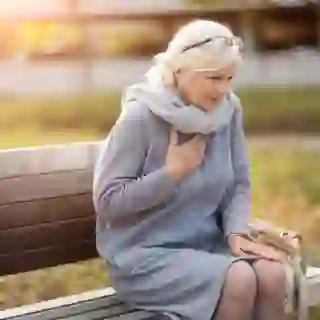 senior woman clutching heart sitting outside