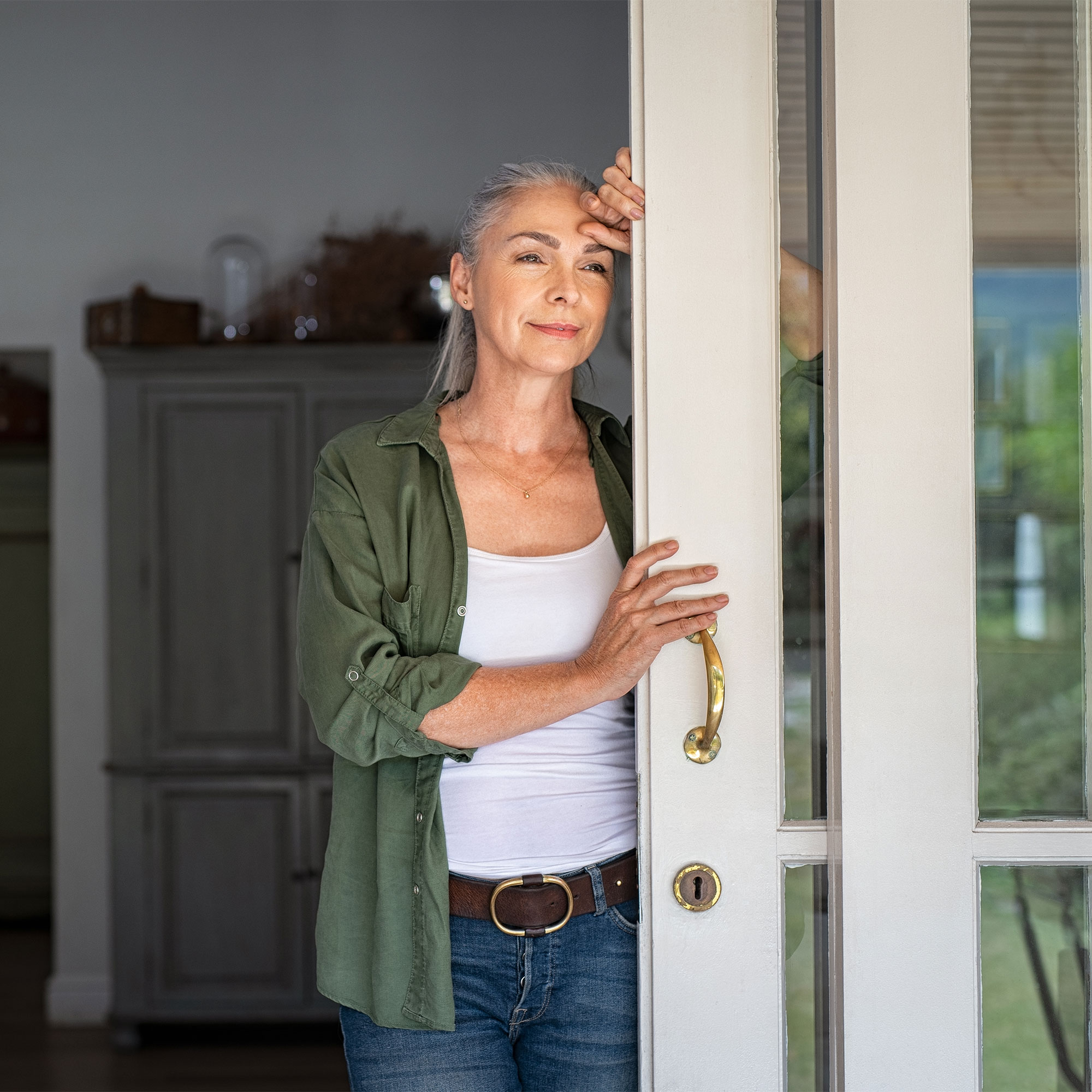 一个沉思的女人靠在家里的门上