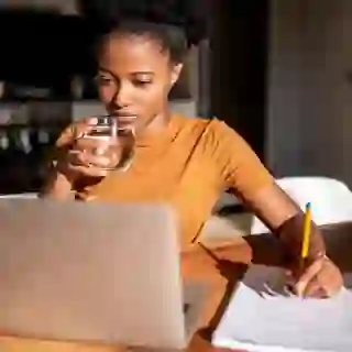 Woman drinking water at computer