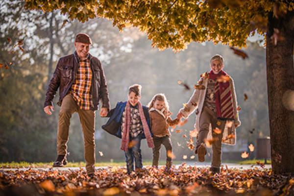 在秋天和孙儿们散步的老年人。
