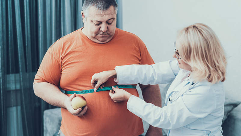 医生测量肥胖男人的腰围尺寸。