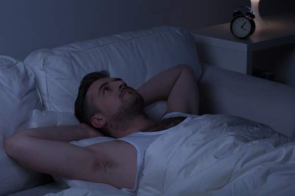 男人在床上在黑暗的房间很清醒