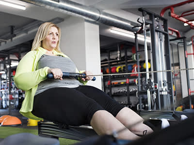 女人在健身房锻炼一个划船机上。