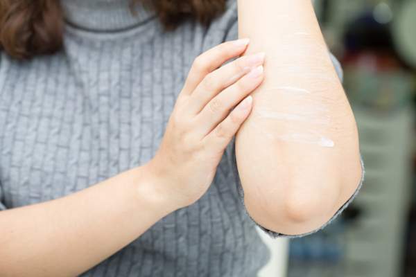 女人把乳液涂在手肘上