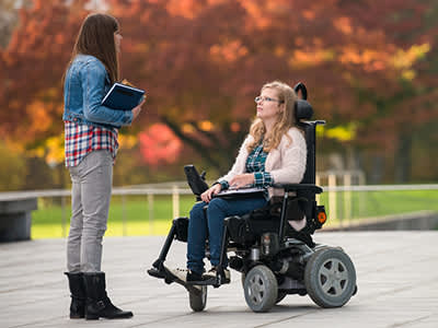 坐在电动轮椅上的女人和朋友聊天。