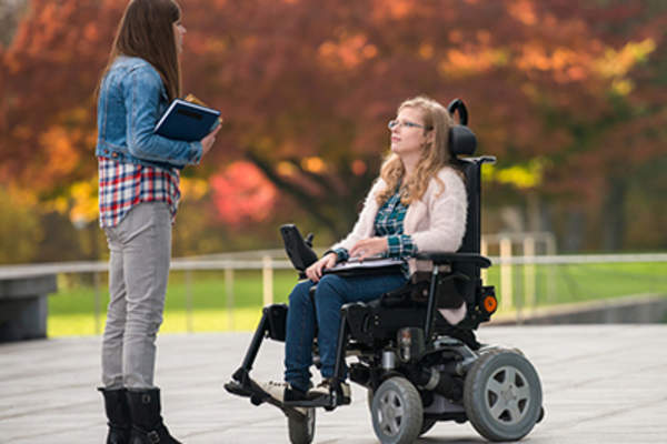 坐在电动轮椅上的女人和朋友聊天。